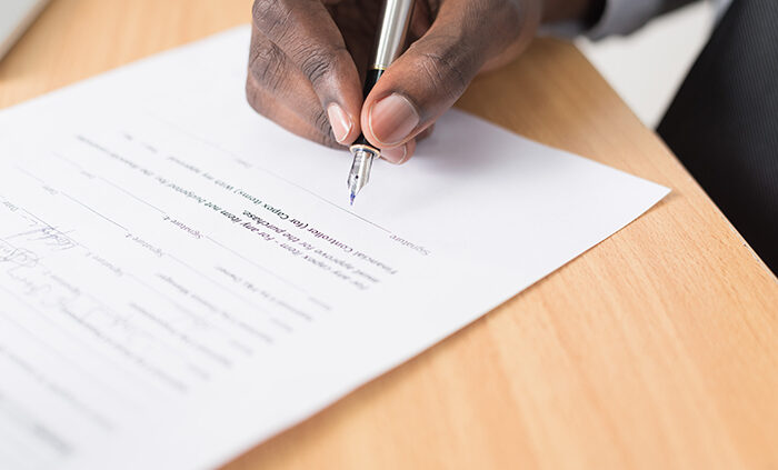 A hand signing a document