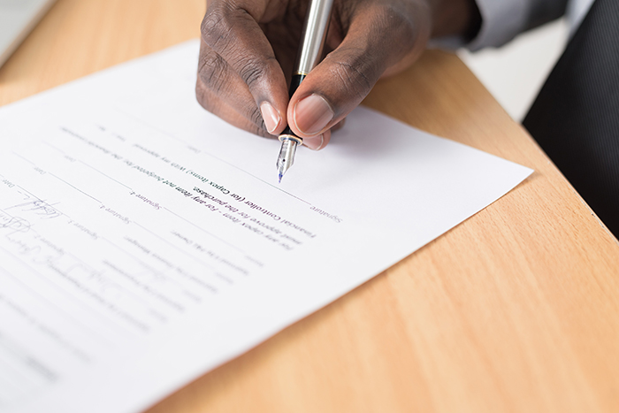 A hand signing a document