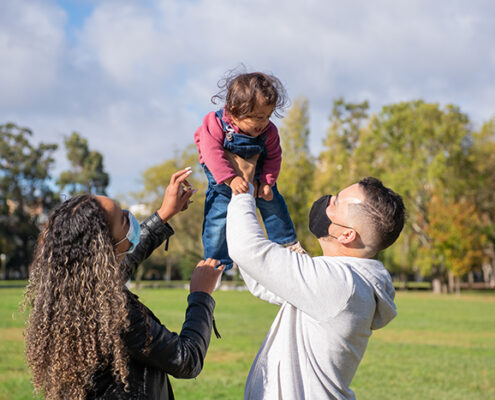 Two parents holding a baby outside.