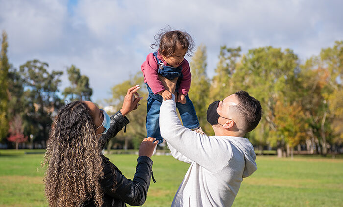 Two parents holding a baby outside.