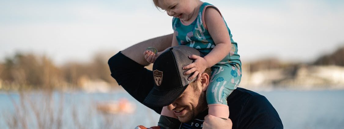 A father carrying his young daughter on his shoulders