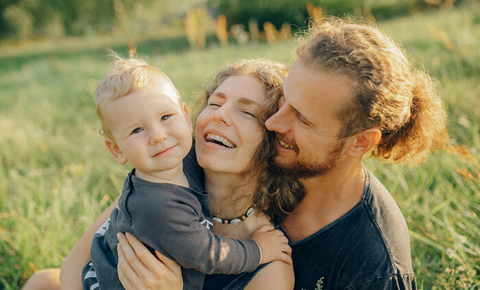 A picture of a smiling mother, father, and young child.