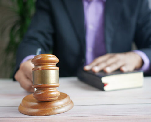 An image of a hand holding a gavel and another hand on the Bible