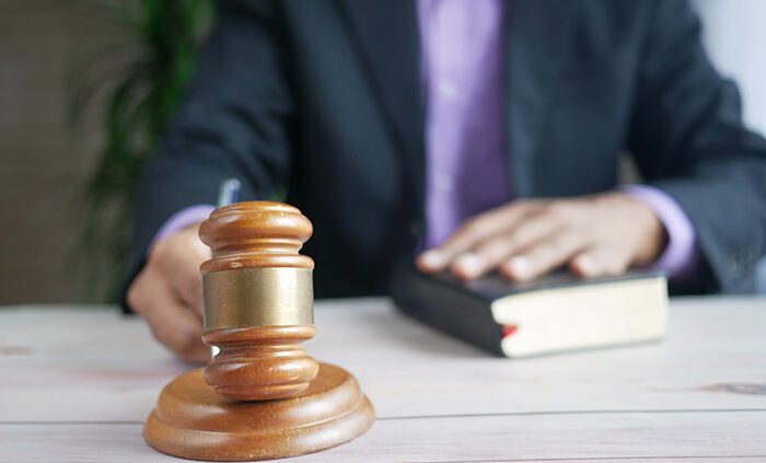 An image of a hand holding a gavel and another hand on the Bible